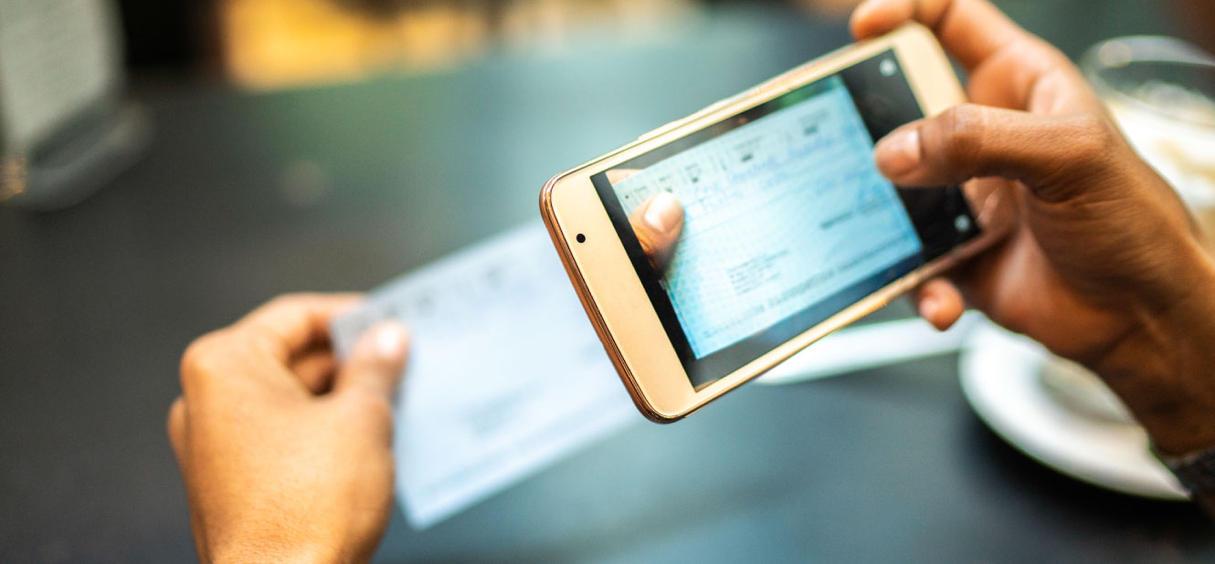 Close up of a person's hands taking a picture of a check with a smartphone